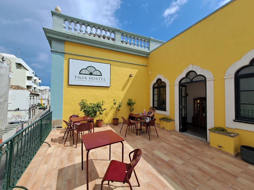 a yellow building with tables and chairs on a deck at Tilia Hostel in Faro