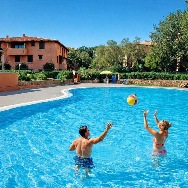a man and woman playing with a beach ball in a swimming pool at Tortuga Smeralda in Porto Rotondo