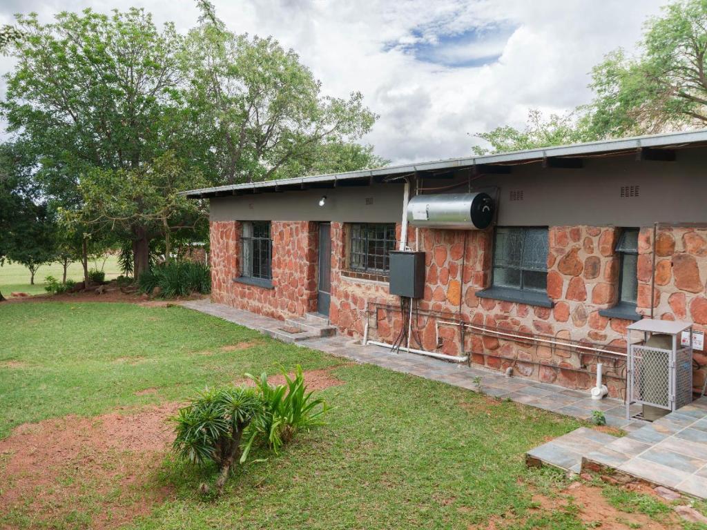 a brick house with a grass yard at Impala Game Ranch in Dinokeng Game Reserve