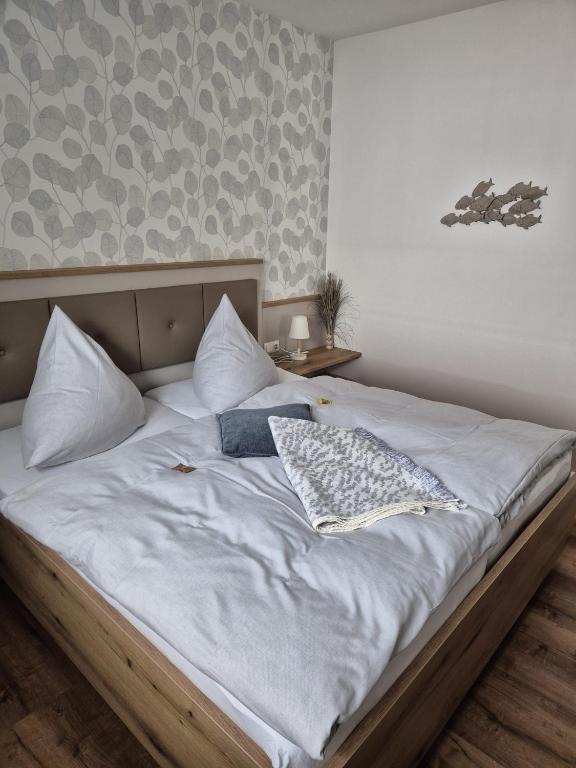 a large bed with white sheets and pillows on it at Kleine Hafenperle Büsum in Büsum