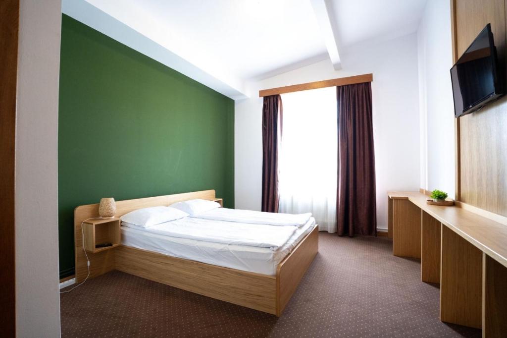 a bedroom with a bed and a green wall at Rákóczi Center in Odorheiu Secuiesc