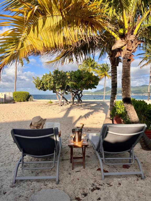 two chairs and a table on a beach with palm trees at Sole e Mare NBBC sur la plage de Baie Nettlé in Baie Nettle