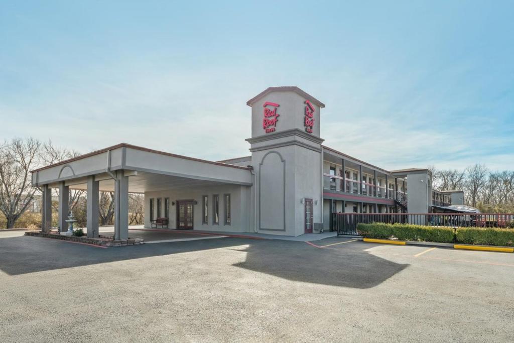 a large white building with a clock tower at Red Roof Inn Ardmore in Ardmore