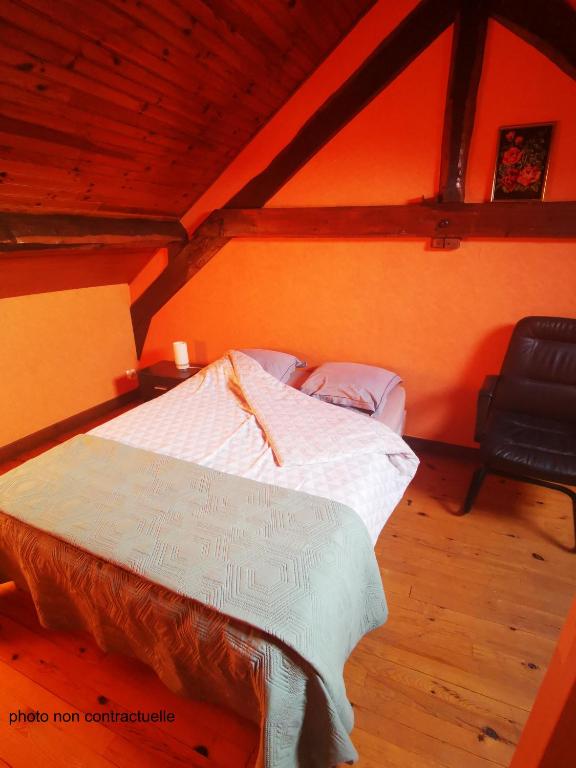 a bedroom with a bed and a black chair at Les racines Bohèmes in Avèze