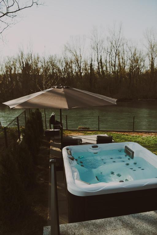 a hot tub with an umbrella next to a body of water at A frame CHILL House in Brasina