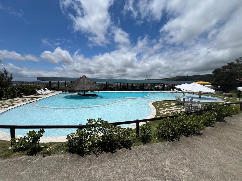 a large blue swimming pool with a umbrella and the ocean at Flat on Mount Castelo Sairé in Sairé