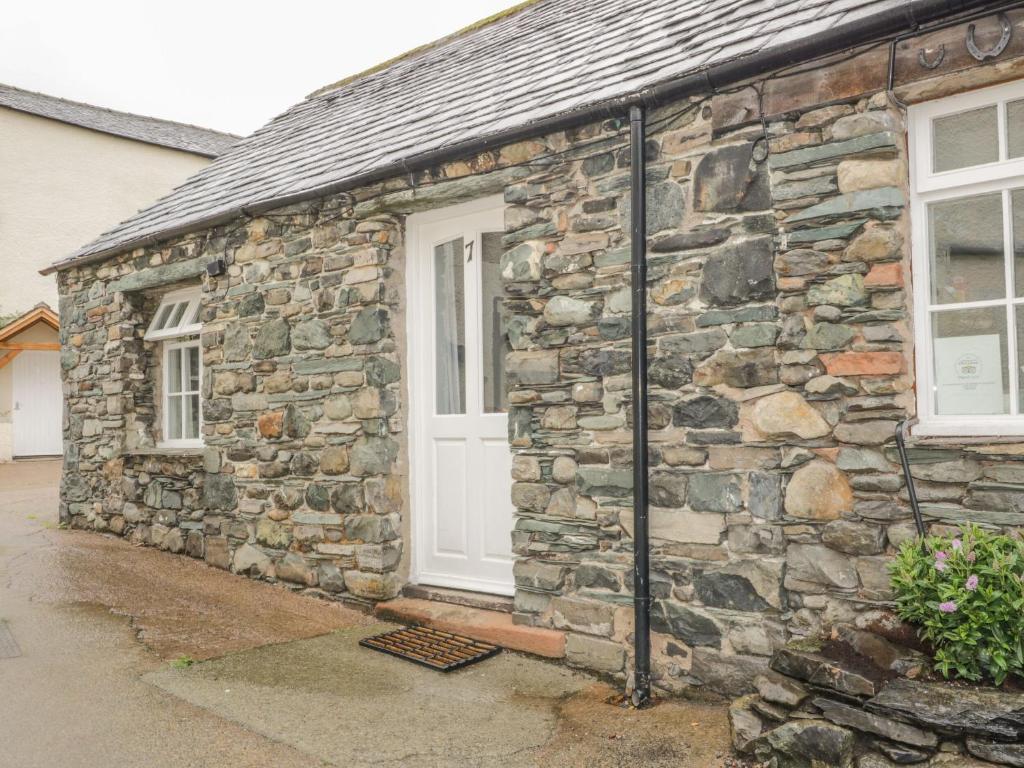 a stone building with a white door and windows at Mews Cottage 7 in Keswick