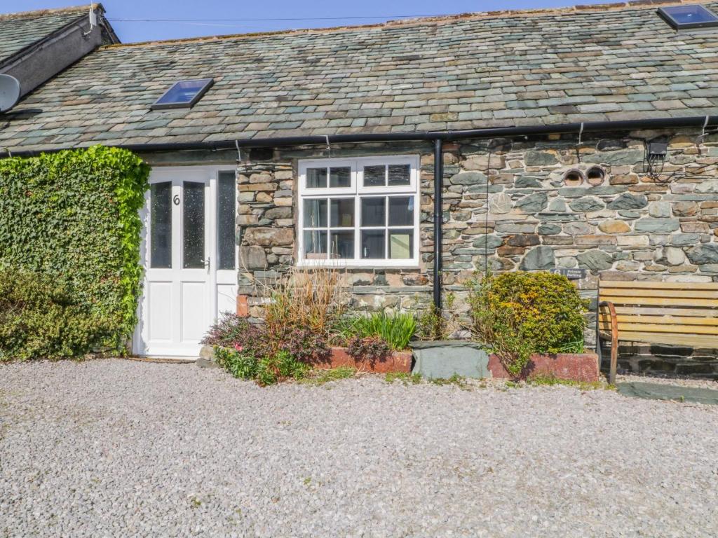 a stone cottage with a white door and a bench at Mews Cottage 6 in Keswick