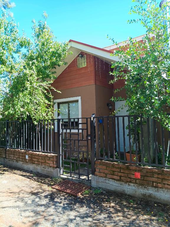 a fence in front of a house with trees at EL ROBLE 2 CHILLaN in Chillán