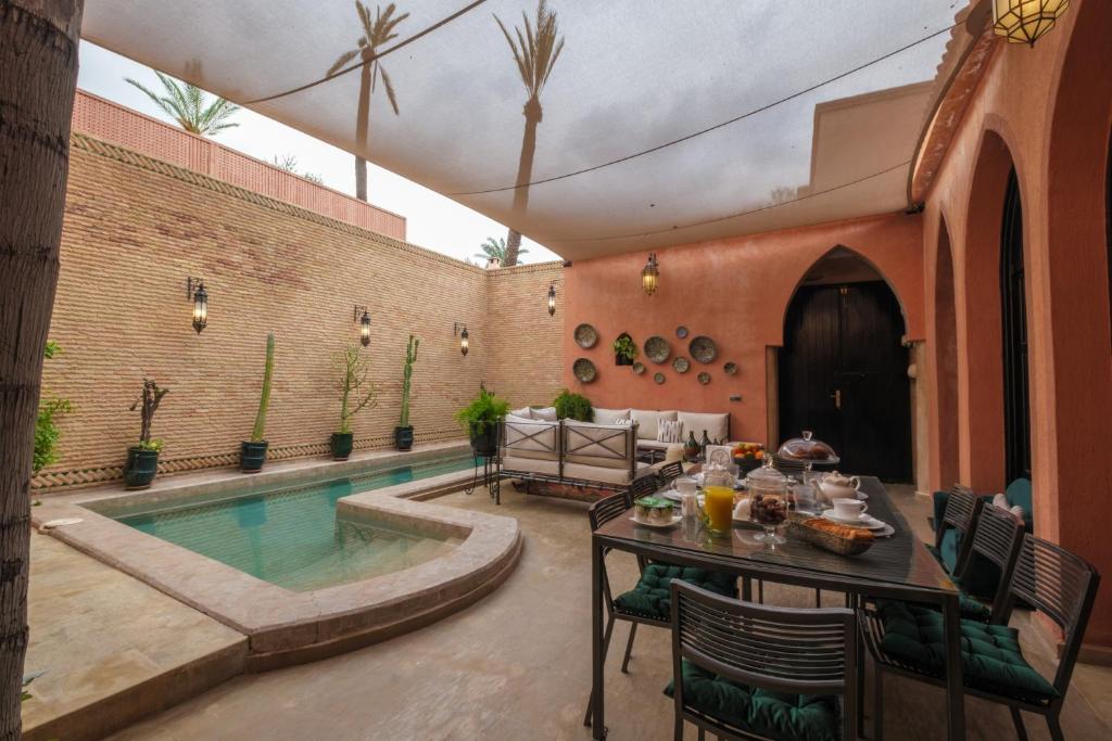a patio with a table and a swimming pool at Riad Malak Palmeraie in Marrakesh
