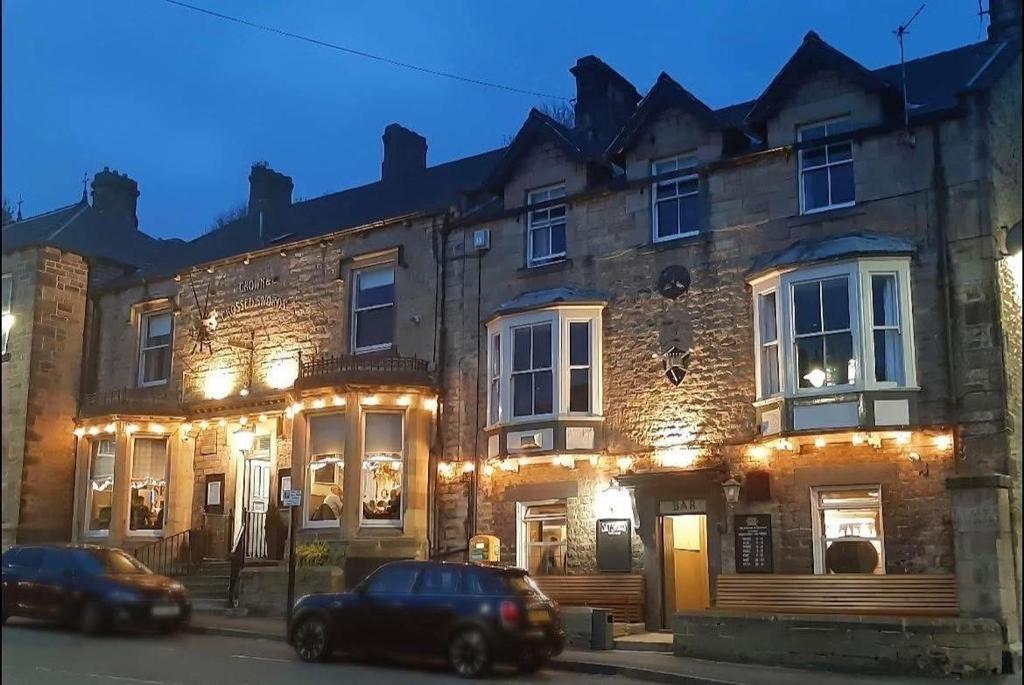 two cars parked in front of a building with lights at Crown & Crossed Swords in Shotley Bridge
