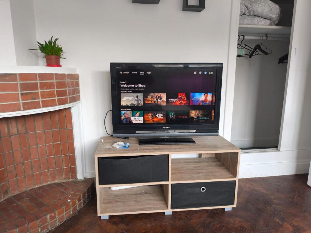 a television on a wooden stand in front of a fireplace at Le 5BG Signature in Dunkerque