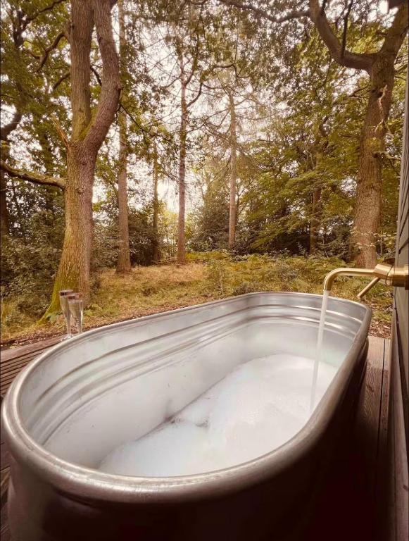 a bath tub sitting on a deck with a tree at The Bodos Hut in Lintz Green