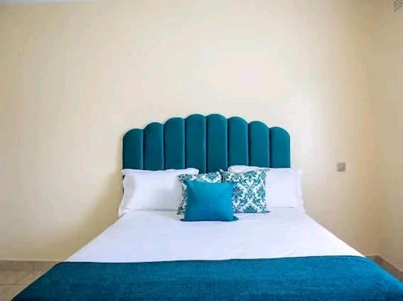 a bedroom with a blue and white bed with pillows at Cozy Corner Monavale in Harare