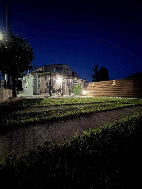 a house lit up at night with a fence at Alexandra Apartment in Agíasma