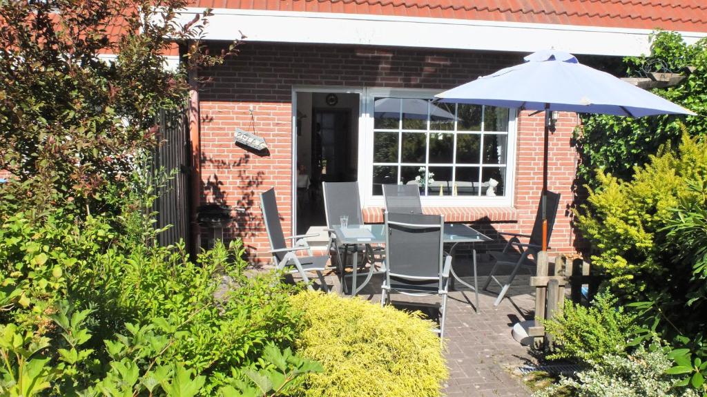 a patio with a table and chairs and an umbrella at Kaptains Koje in Wittmund