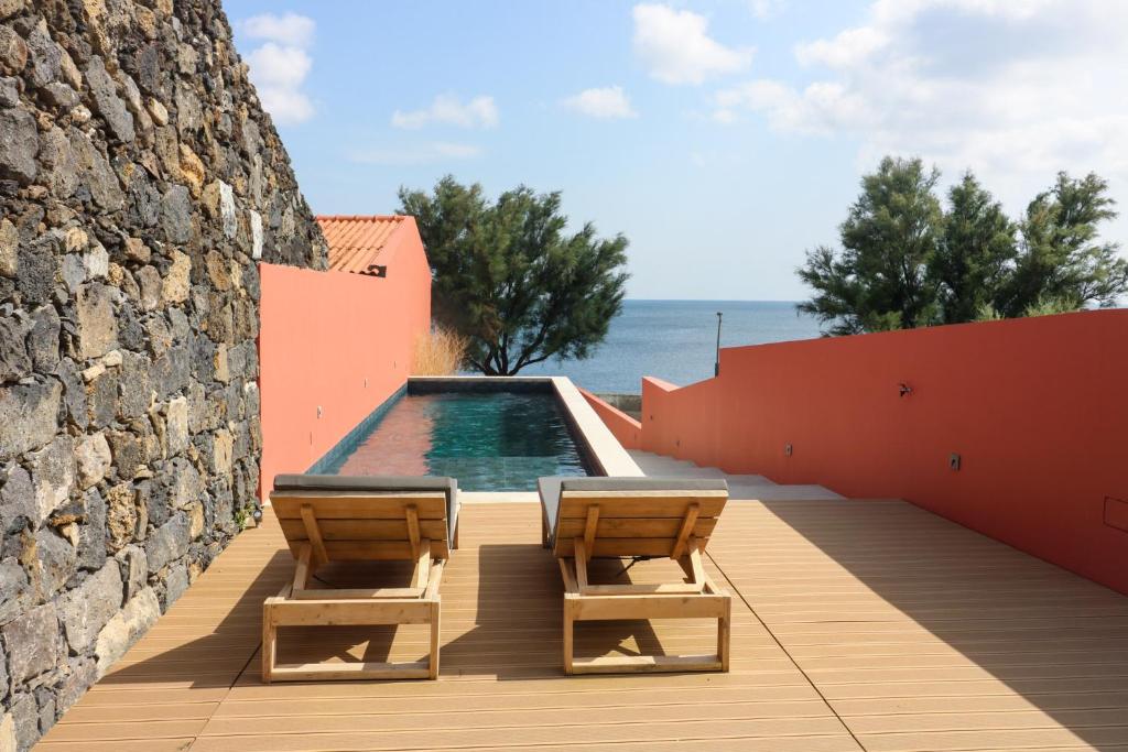 two chairs and a swimming pool next to a wall at Villa São Roque in Ponta Delgada