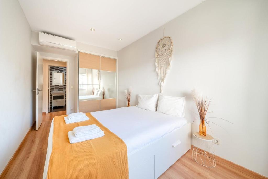 a white bedroom with a large bed with a wooden floor at GuestReady - Retreat in Almada in Almada