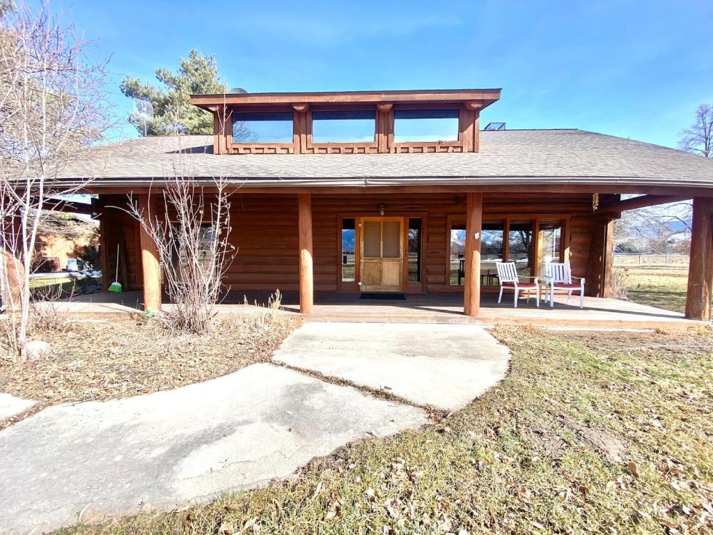 a large wooden house with a porch and two chairs at Selway View Cabin in Corvallis