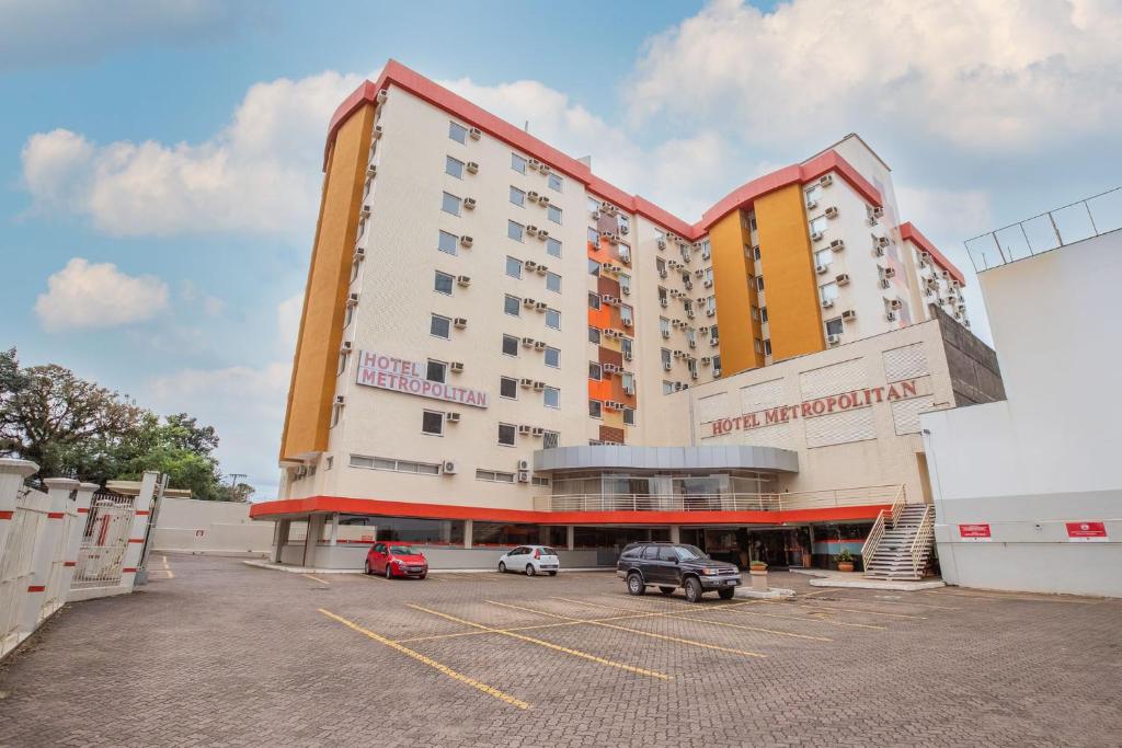 a large building with cars parked in a parking lot at Hotel Metropolitan Canoas in Canoas