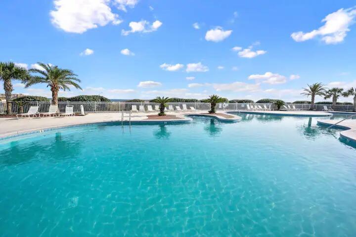a large swimming pool with blue water and palm trees at Salty Dune 2BR Beach Condo w Pools in Gulf Shores