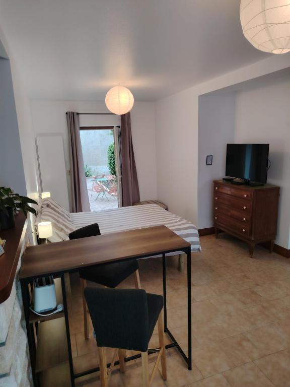 a living room with a table and a television at Studio Magnolia in Saint-Satur
