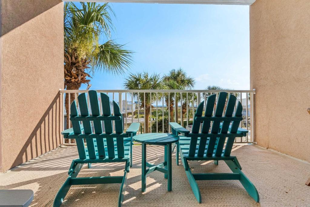 two green chairs sitting on a balcony with the ocean at Sunsets and Palms in Gulf Shores