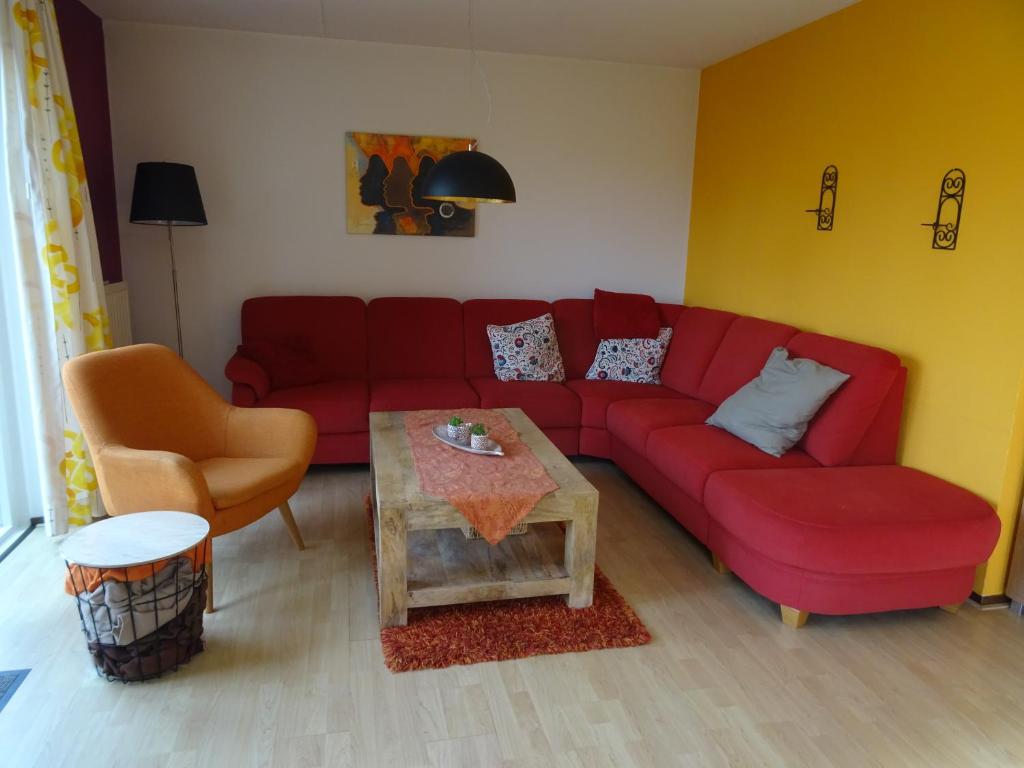 a living room with a red couch and a table at Kustverhuur, Park Scheldeveste, Zwin 022 in Breskens
