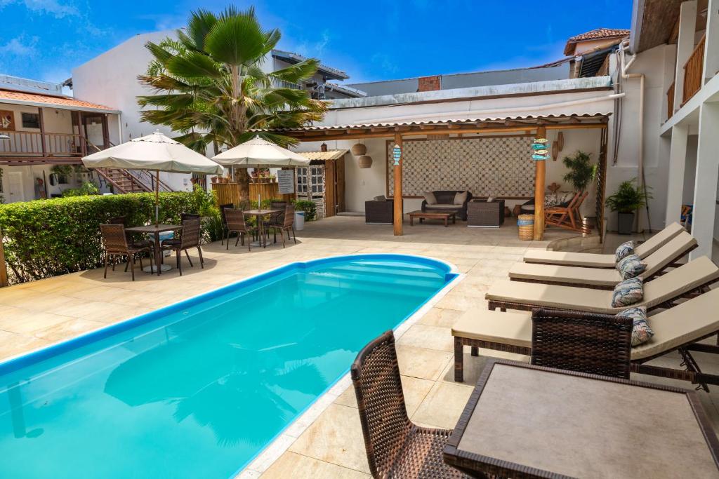 a swimming pool with chairs and tables and a patio at Pousada Jangadeiro in Porto Seguro