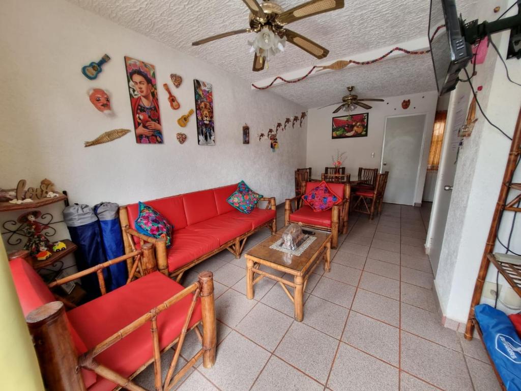 a living room with a red couch and chairs at Casa de playa El Artesano in Ixtapa