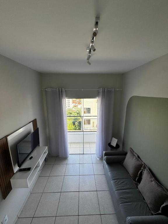 a living room with a couch and a television at Apartamento com varanda in Lavras