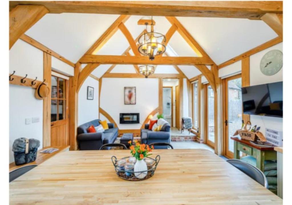 a dining room and living room with a large wooden table at The Saddlery Barn Retreat in Ashford