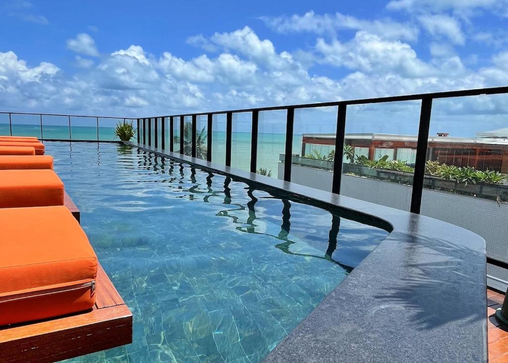 a swimming pool with a view of the ocean at Edition 201- Flat aconchegante no Cabo Branco - ASKA in João Pessoa