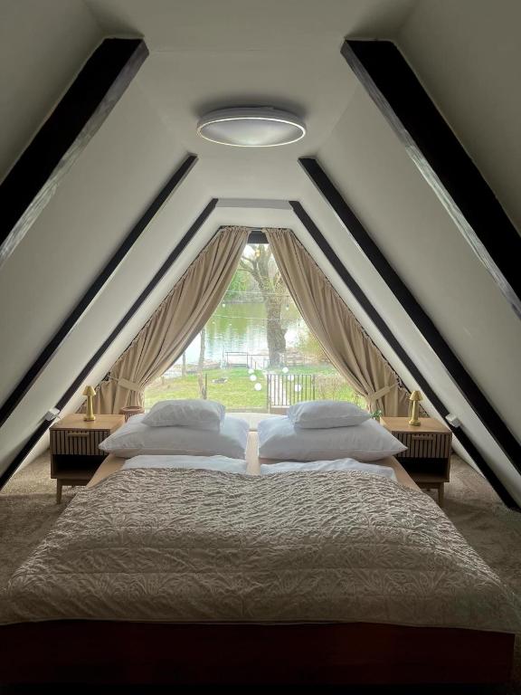 a bedroom with two beds and a window at LODKA Vendégház in Szigetcsép
