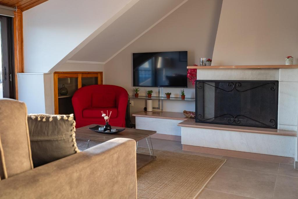 a living room with a fireplace and a red chair at Atticview Oropos in Néa Palátia