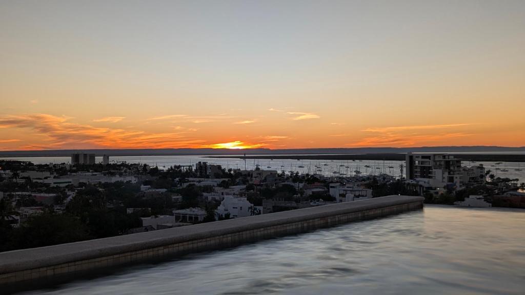 a view of a city with the sunset in the background at Vista Cortes 2BR 2BA Condo - Walk to the Malecon! in La Paz