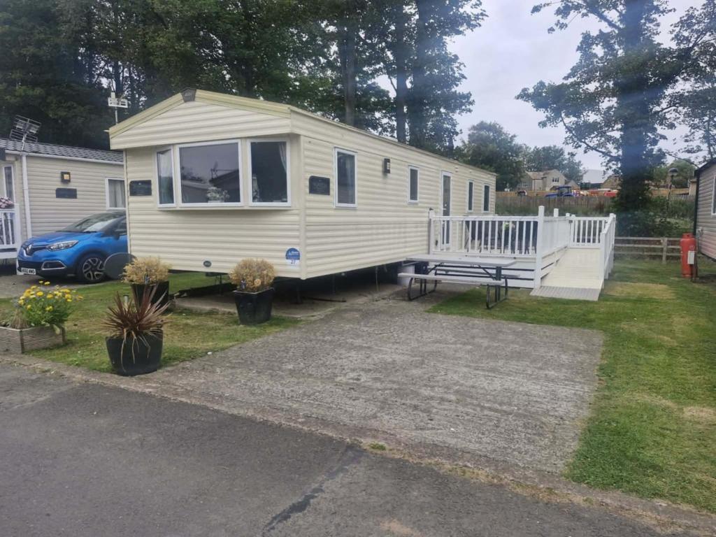 a white tiny house with a porch and a bench at haggerston castle lakeside east 27 in Goswick Station