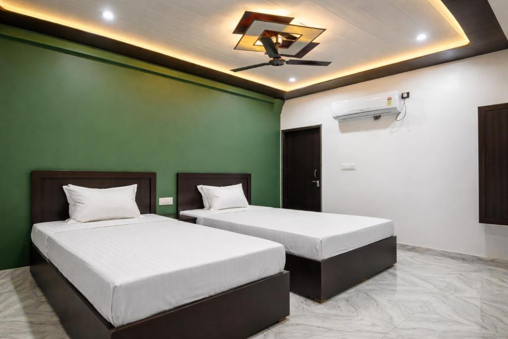 two beds in a room with green walls and a ceiling at kanakdhara aashraya in Vrindāvan