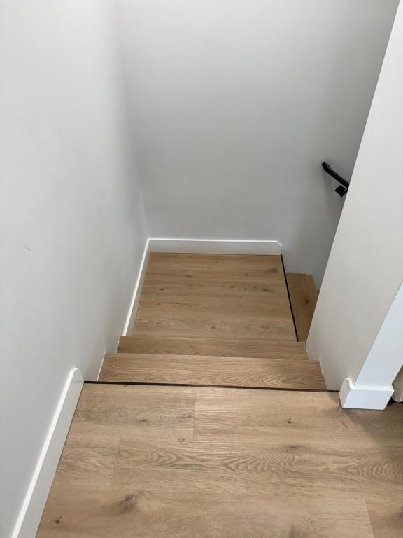an empty room with a staircase with wooden floors at Modern Townhouse Room in Fredericton