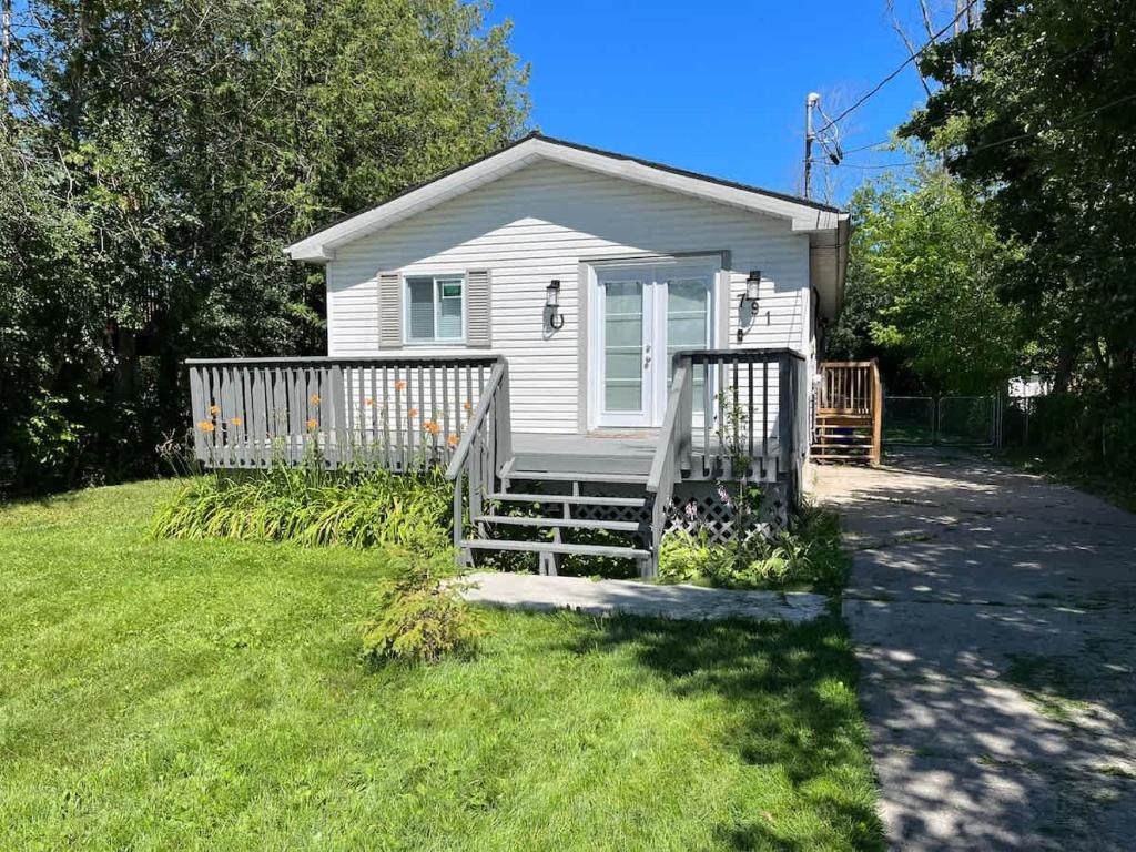 a small white house with a porch and a gate at Lake Simcoe Beach Oasis with Backyard and Firepit in Georgina