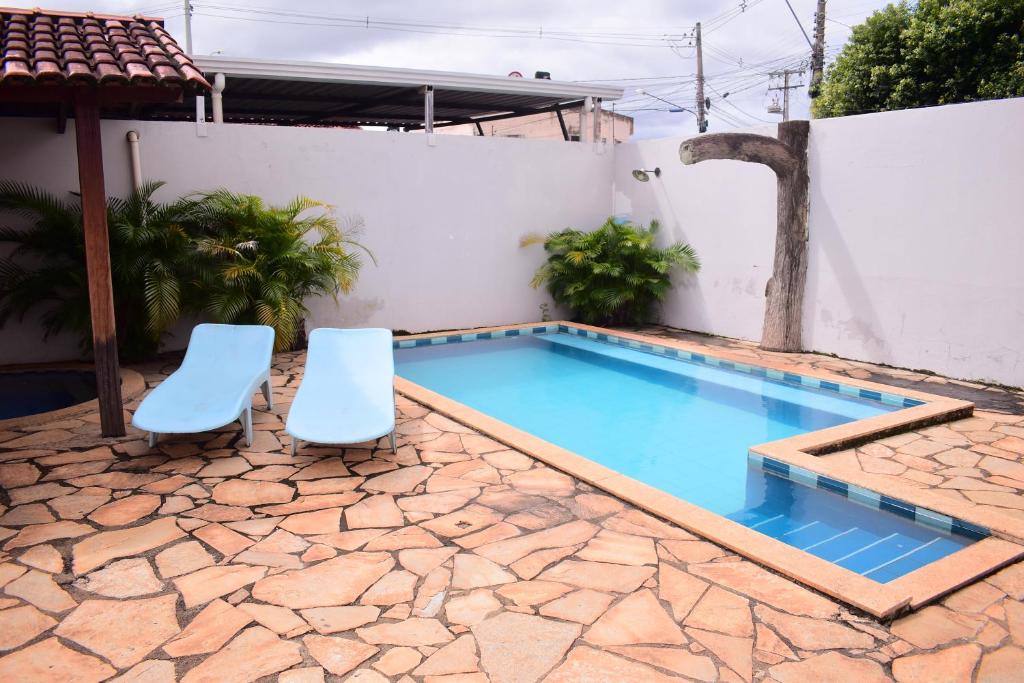 a pool with two chairs next to a house at Hotel Imperador Caldas Novas - GO - Facil acesso aos parques aquaticos e polo gastronômico noturno in Caldas Novas
