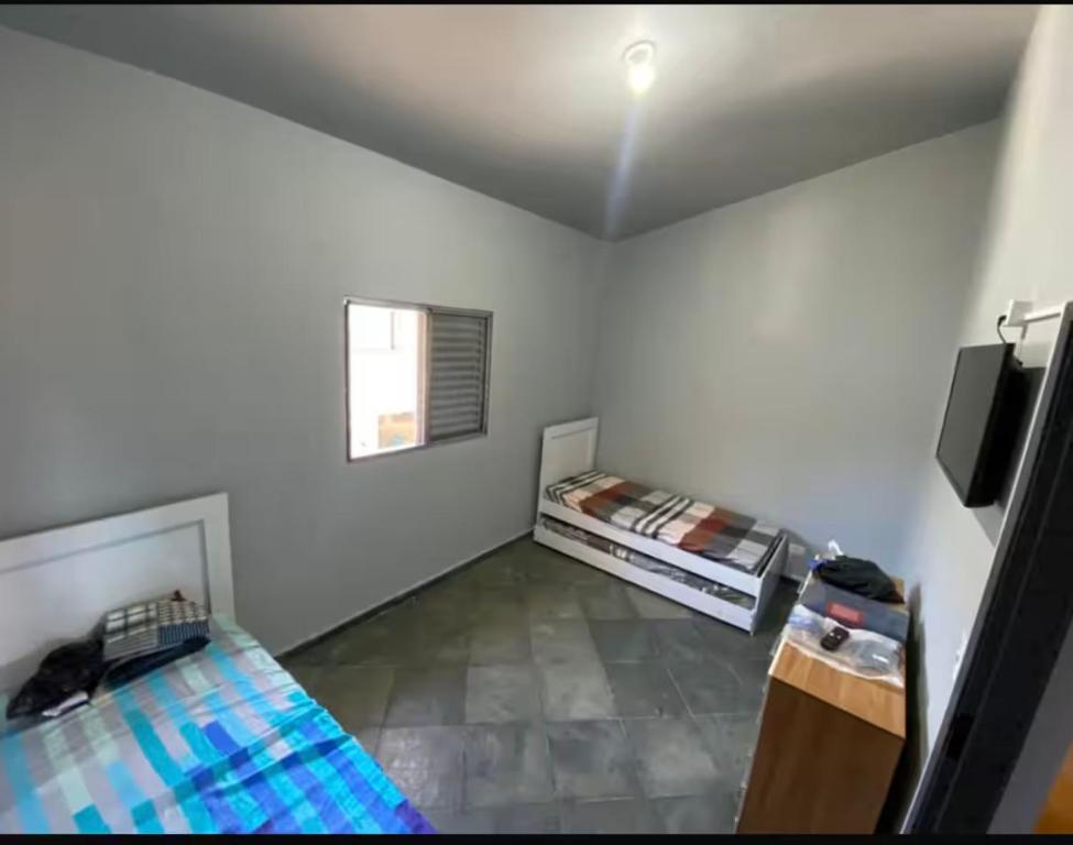 a white room with two beds and a window at Seu Refúgio no Guarujá in Guarujá