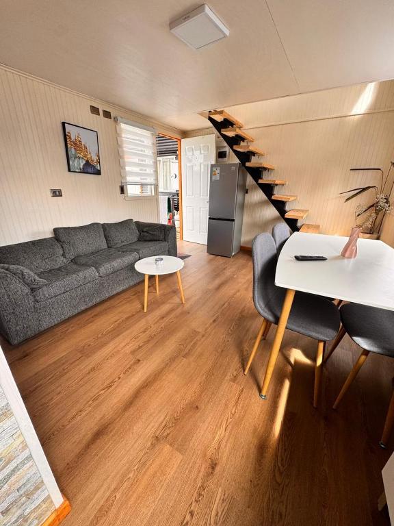 a living room with a couch and a table and a staircase at Departamentos Sol del Sur in Quellón