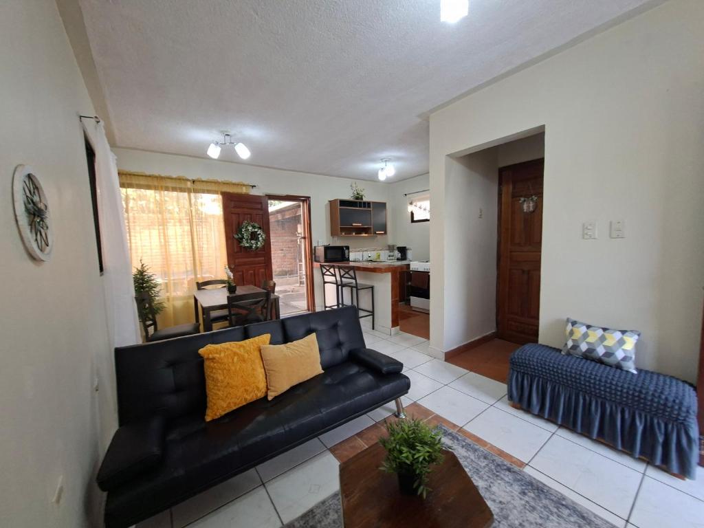 a living room with a black couch and a kitchen at Tulip House in Comayagua