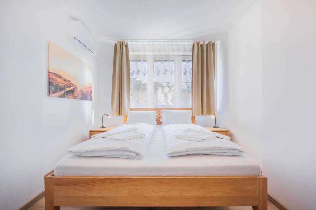 a bedroom with a bed with white sheets and a window at Penzion U Leopolda in Brno