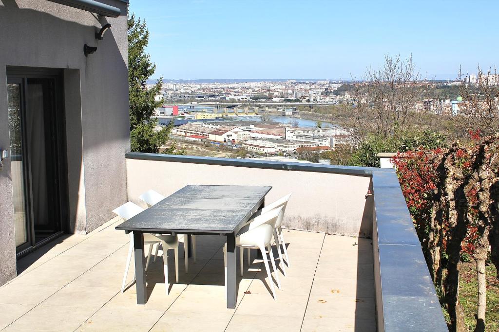 a table and chairs on the balcony of a house at Villa avec vue - terrasse - parking in Irigny