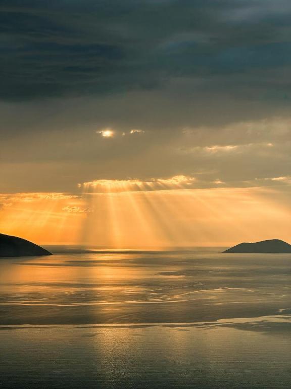 a sunset over the ocean with the sun shining on the water at Festim Villa Hotel in Kaninë