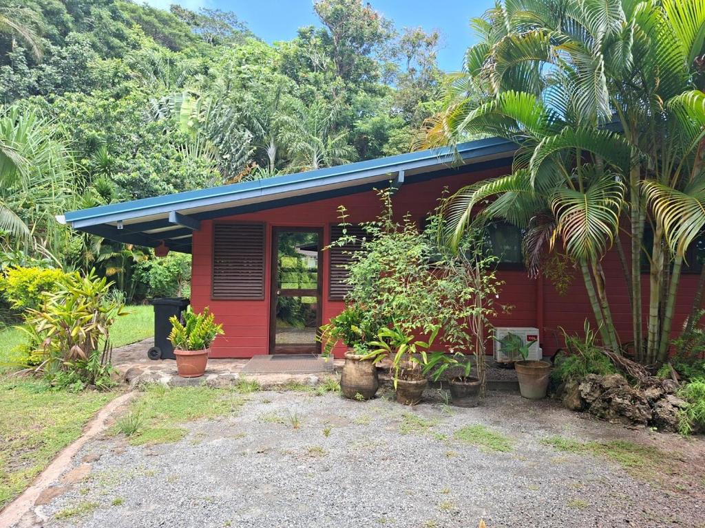 a red house with plants in front of it at Maison avec bungalow Ylang in Uturoa
