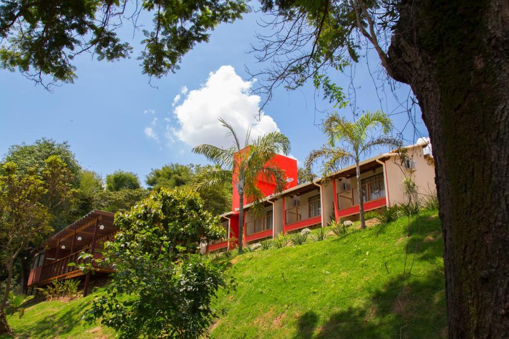 un edificio rojo en la cima de una colina verde en Pousada Verde Villas, en Brumadinho