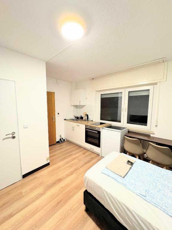 a white room with a bed and a kitchen at Studio Apartment next to Airport in Kelsterbach
